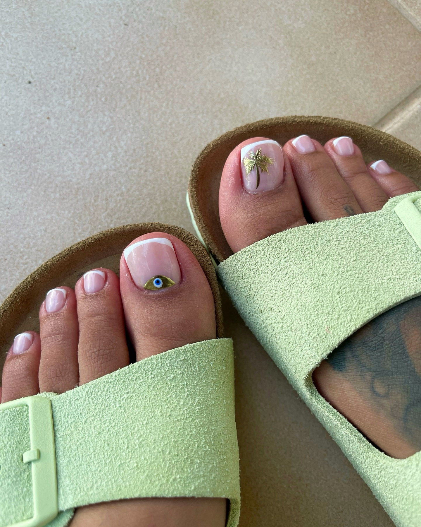 Classic French tip pedicure with palm trees and evil eye pattern