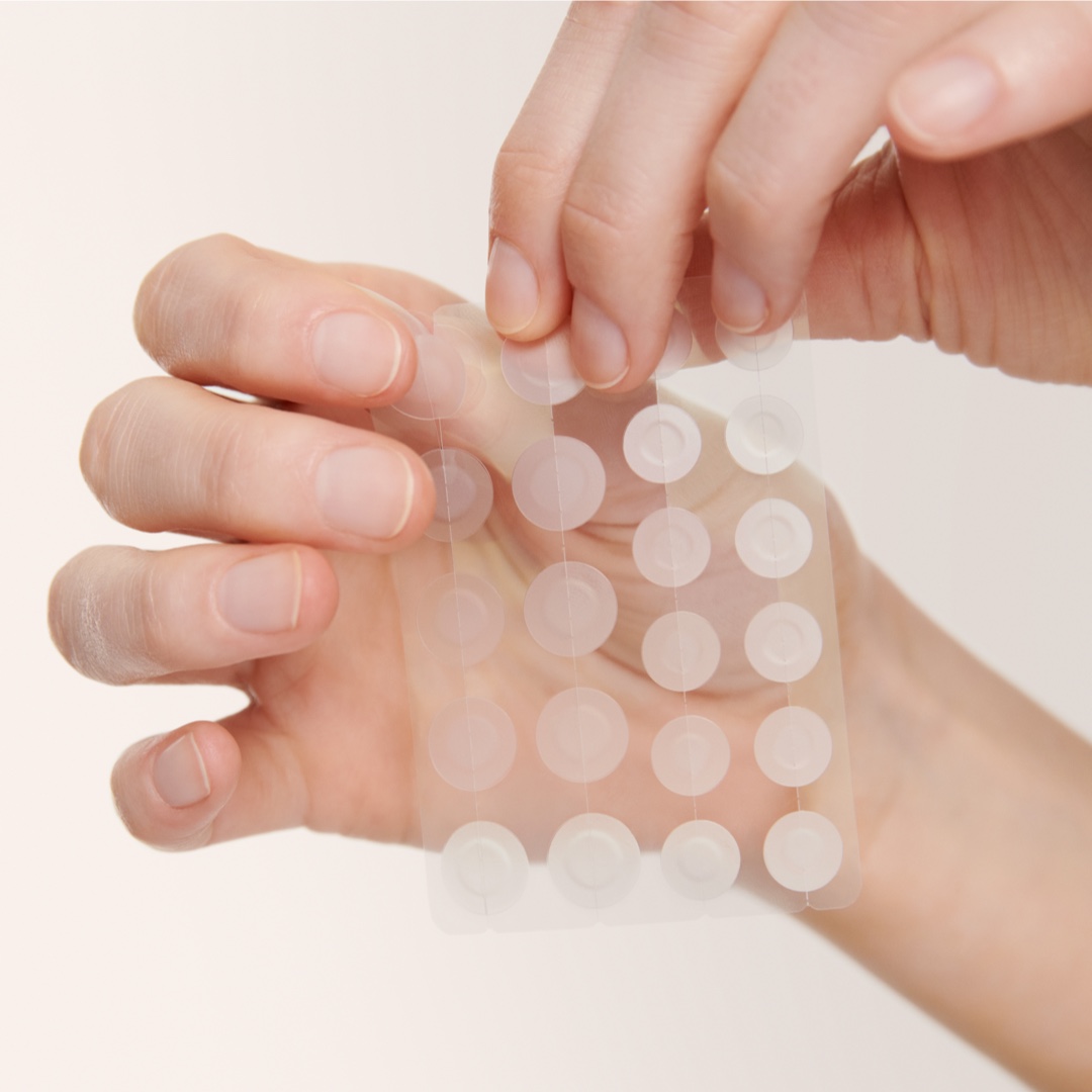 Someone peeling off an invisible hydrocolloid pimple patch