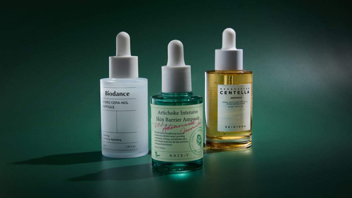 Three Korean skincare ampoules lined up next to one another with dark lighting