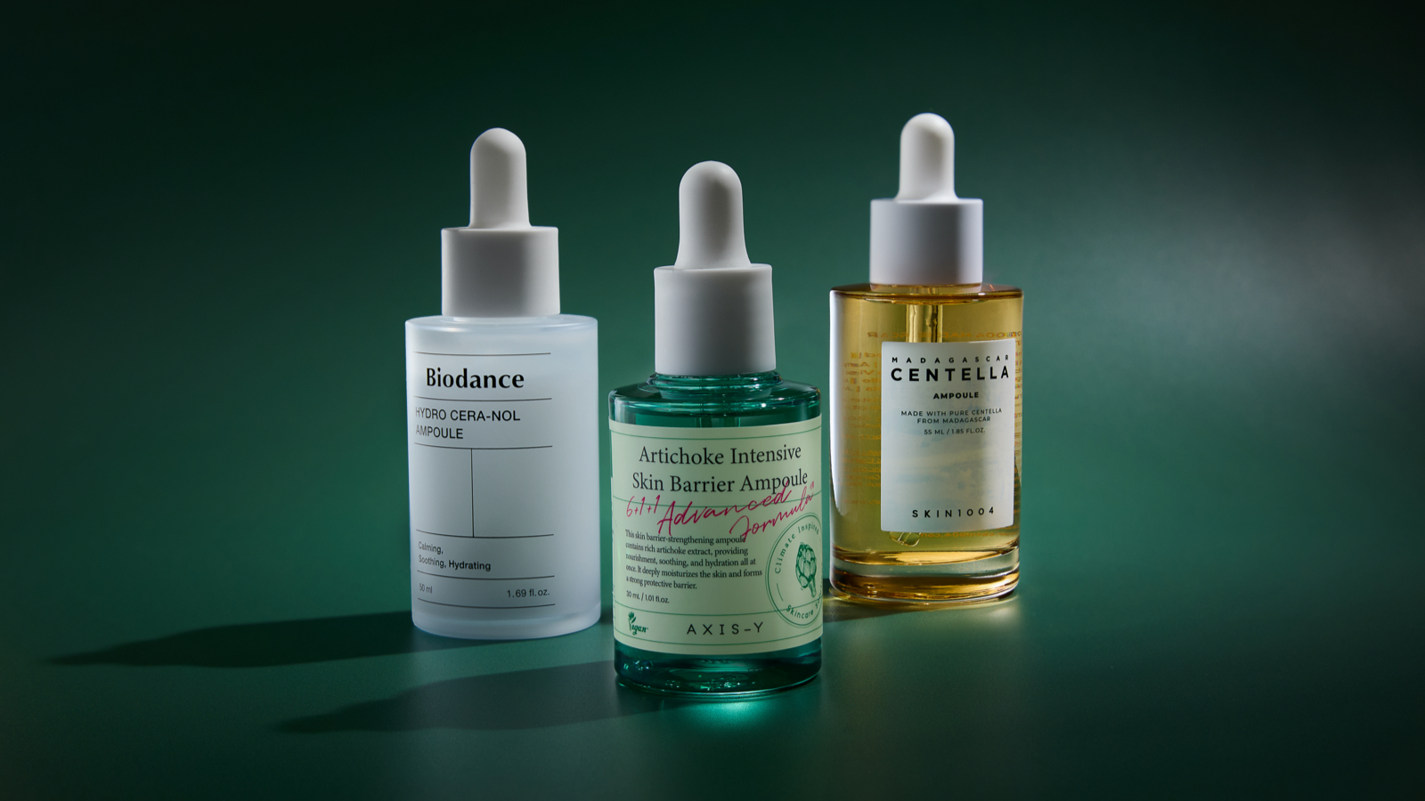 Three Korean skincare ampoules lined up next to one another with dark lighting