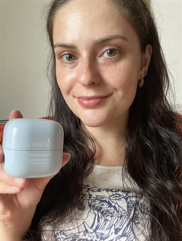 Someone holding up a Laneige moisturiser in blue packaging and with glowy skin
