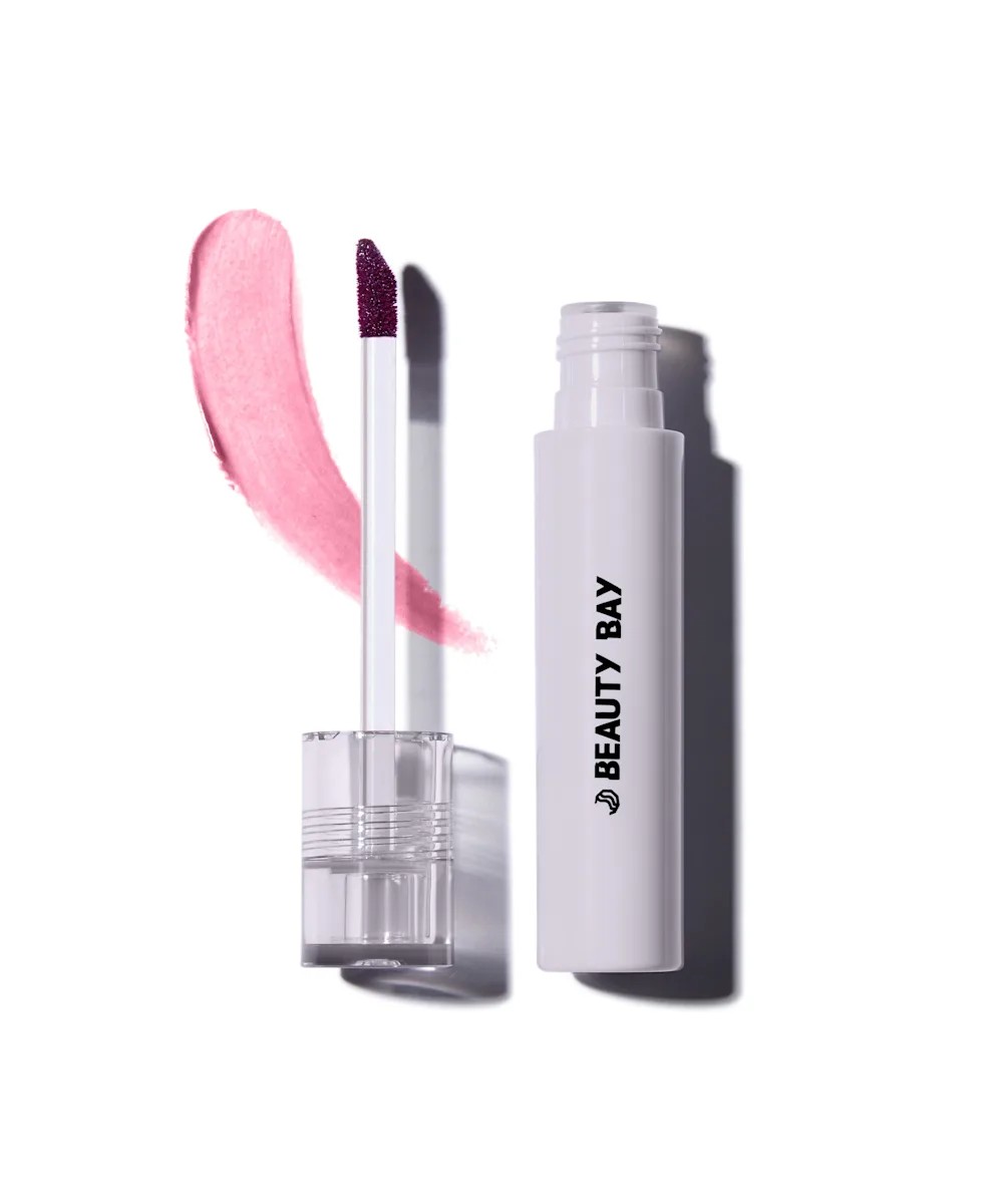 A lip stain product with the lid lying next to the tube, with pink product swatched underneath.