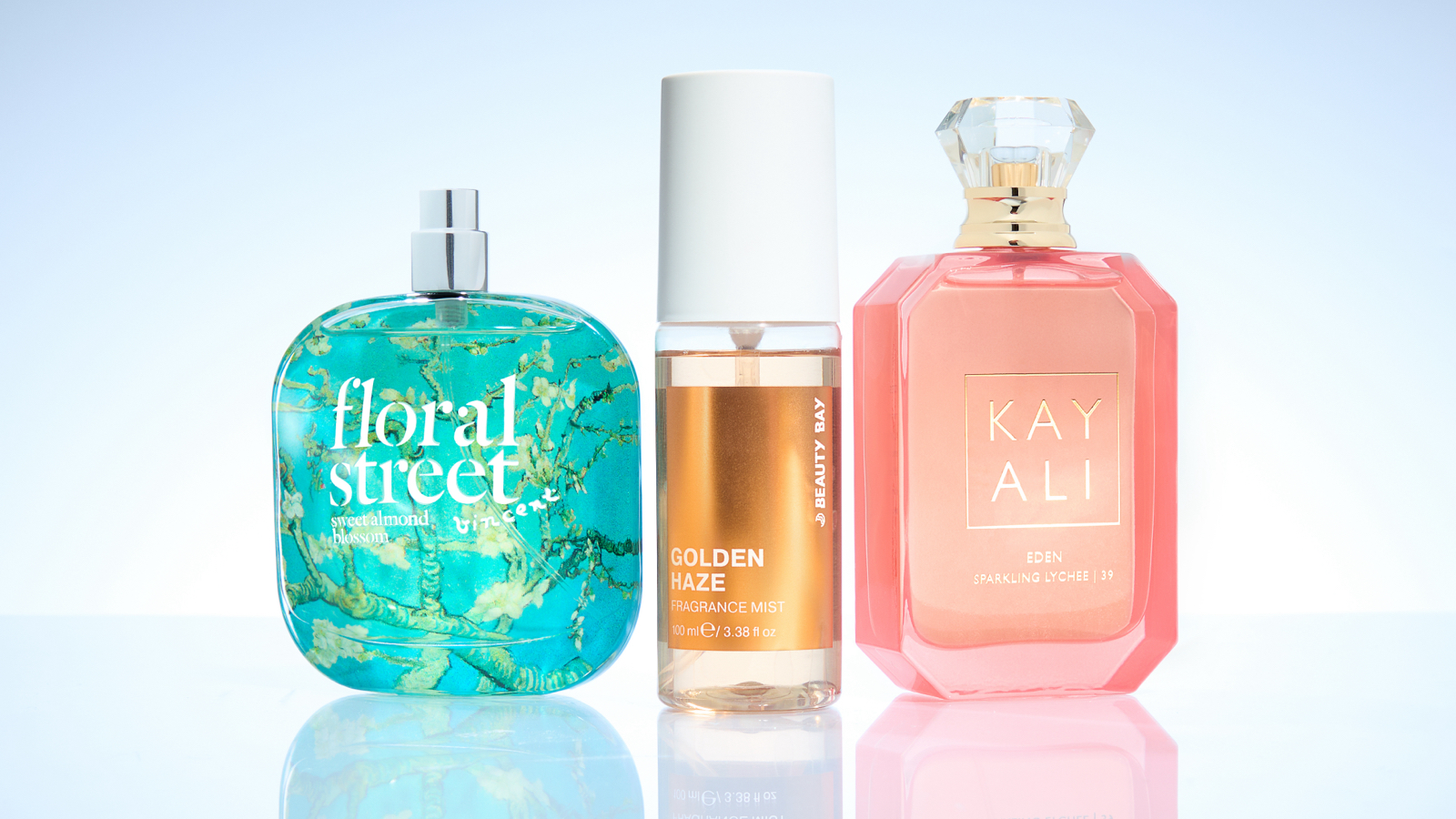 Three summer perfume bottles stood up next to one another on a white background