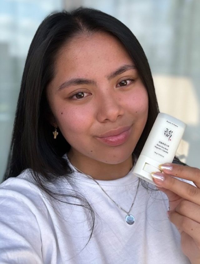 Someone holding the Beauty of Joseon sunscreen stick with glowing skin