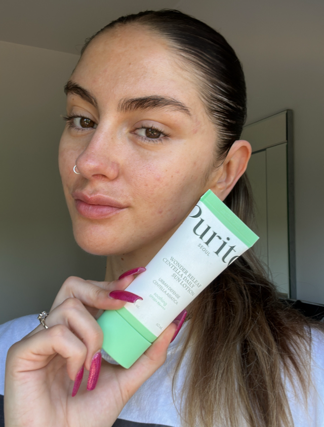 Someone holding the Purito Seoul SPF 50 in a green and white tube