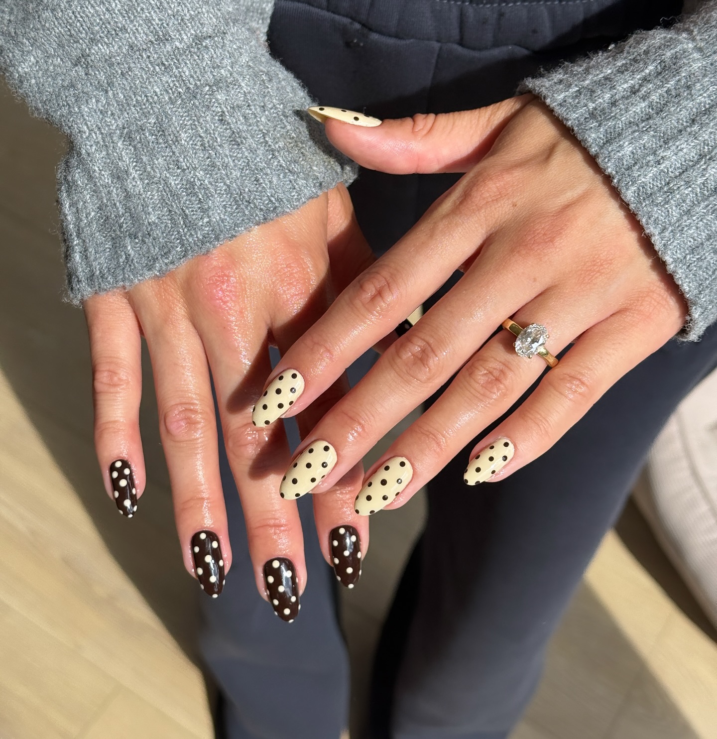 Two hands with opposite polka nails in brown and butter yellow shades