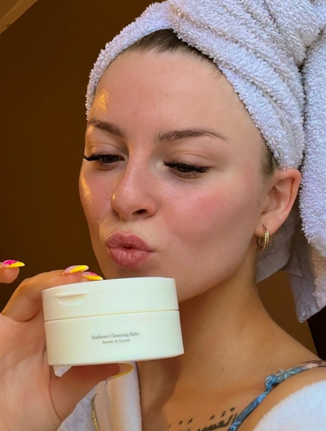 Someone holding a Beauty of Joseon cleansing balm with a towel on their head and fresh skin