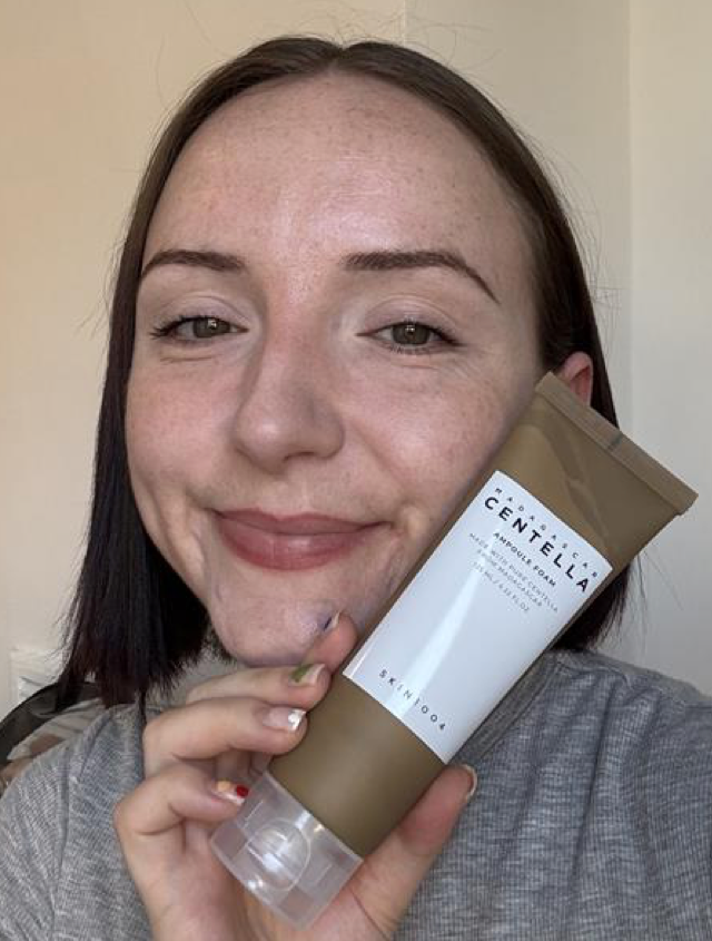 Someone holding the SKIN1004 cleansing foam in brown and white packaging