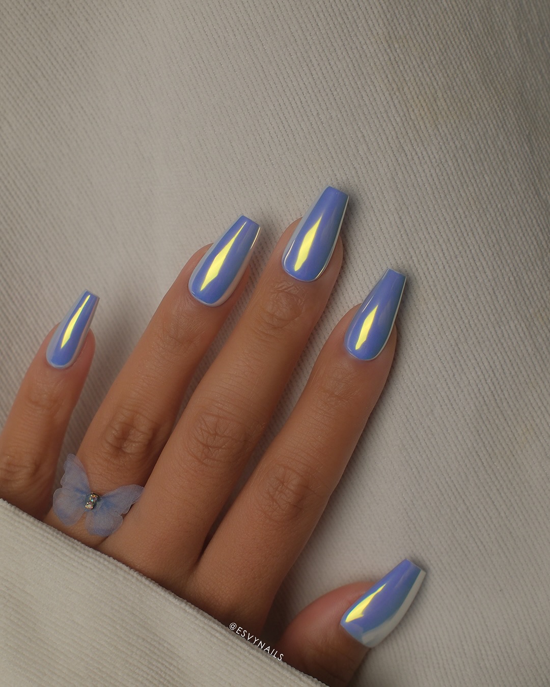 A close up of a hand with lavender coloured chrome nails