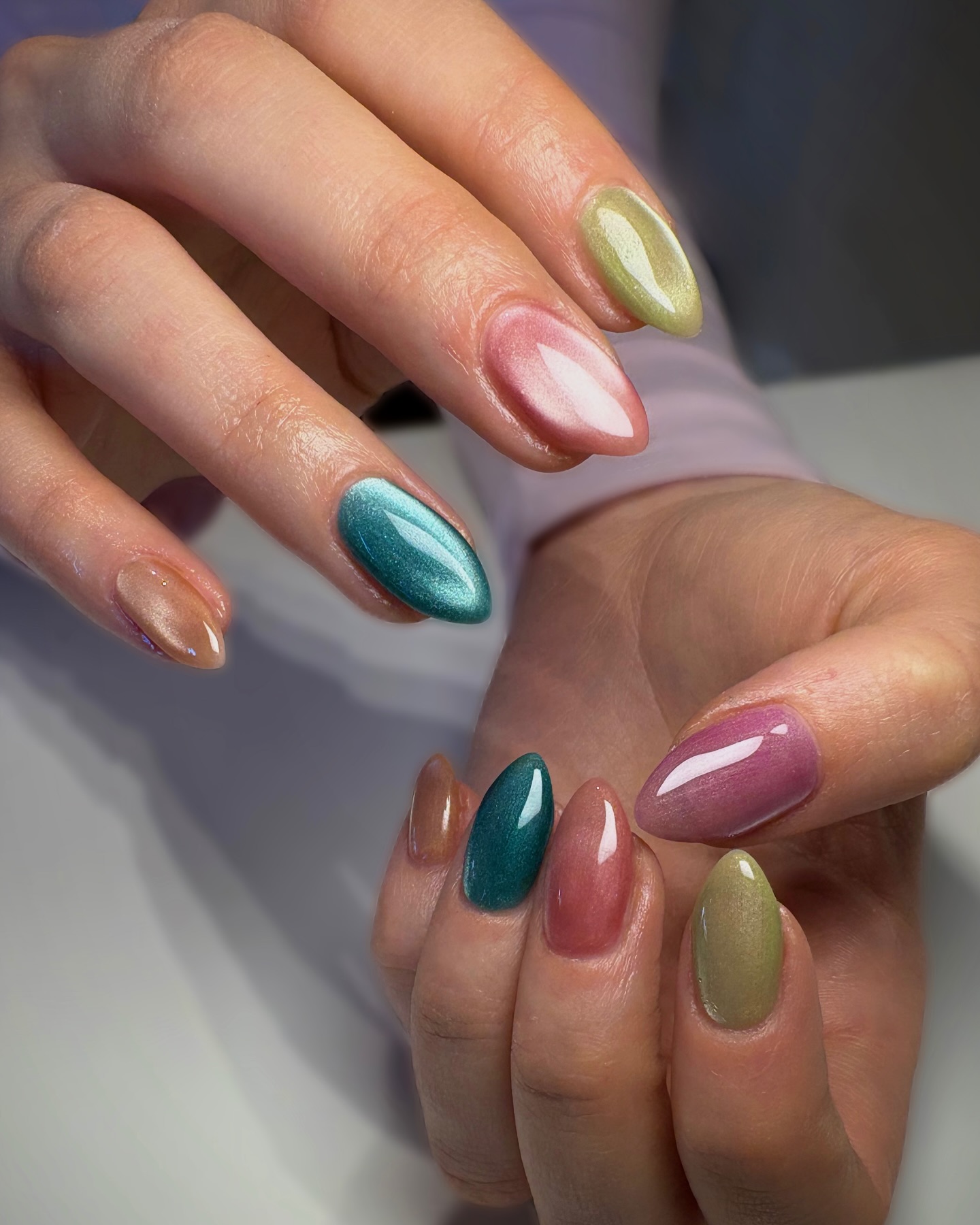 A close up of two hands with a multicoloured jelly nail design