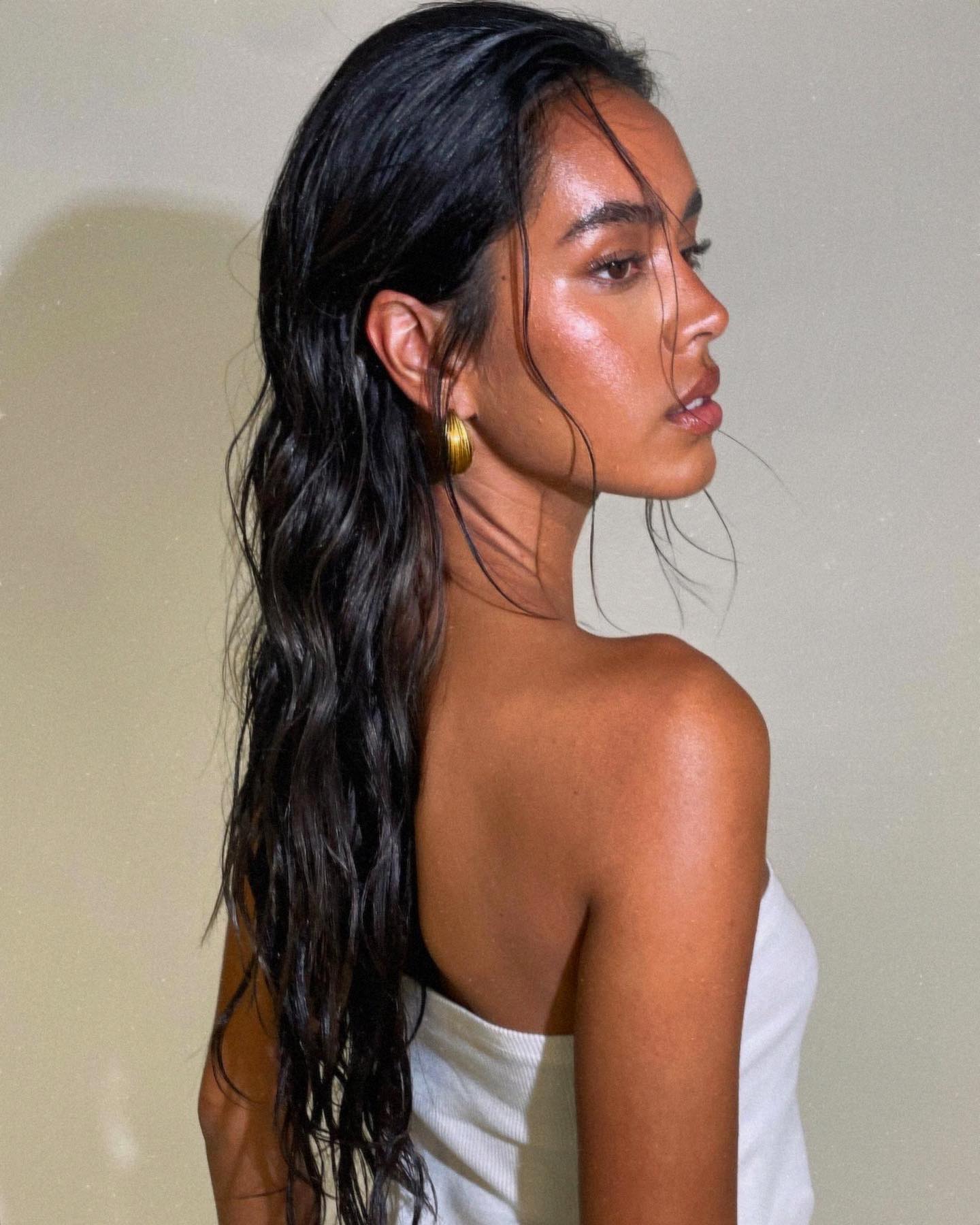 A woman standing side-on with long wavy black hair
