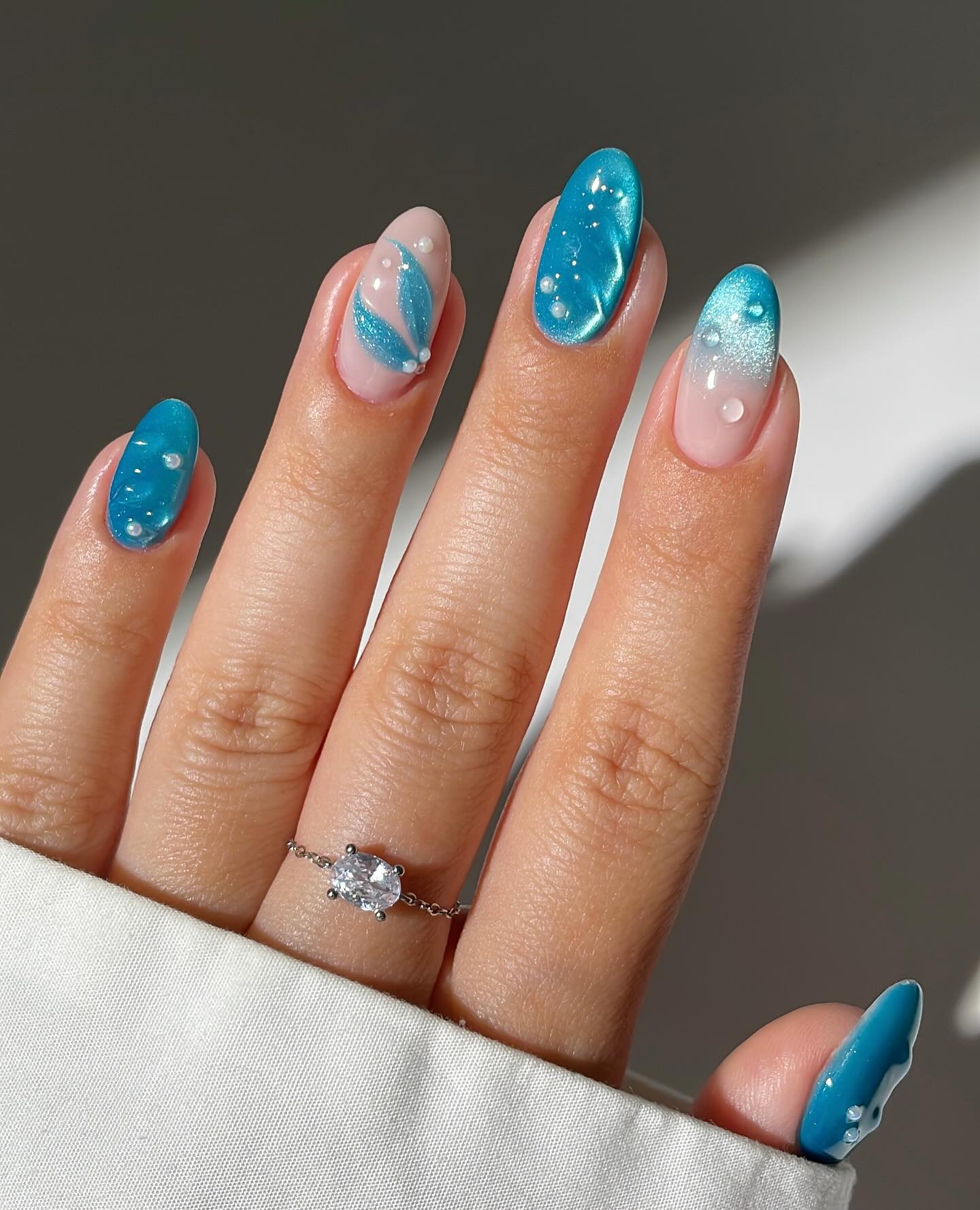 A close up of a hand with almond shaped nails and blue patterns